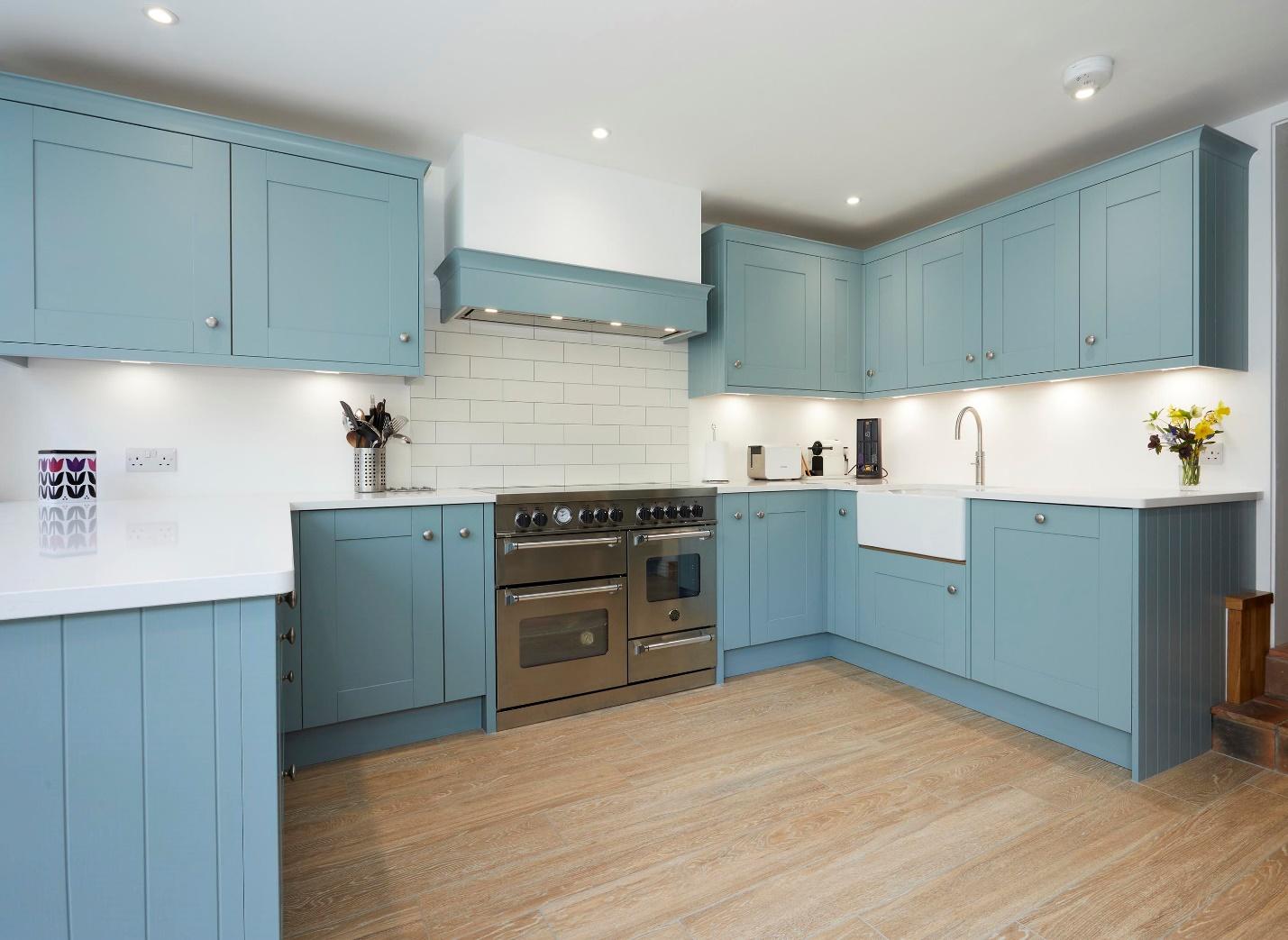 A kitchen with blue cabinets and white counter tops

Description automatically generated